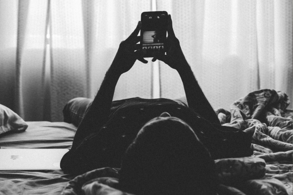 man on the bed typing on his phone
